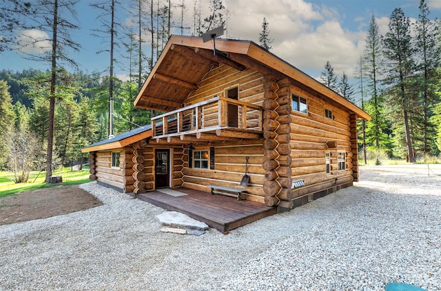 view of side of property with log exterior and a balcony