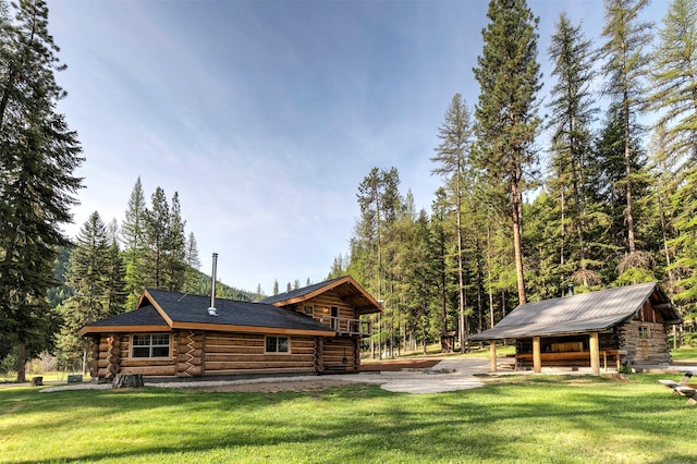 view of property exterior with log siding, a lawn, and a view of trees