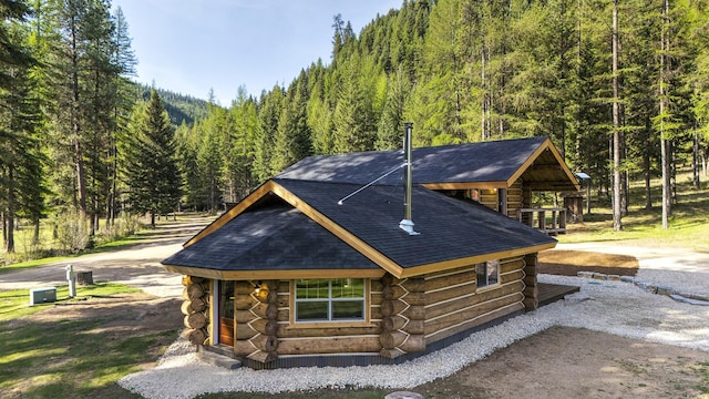 4991 Petty Creek Rd, Alberton, MT 59820 - view of front of house with log exterior, a wooded view, and roof with shingles