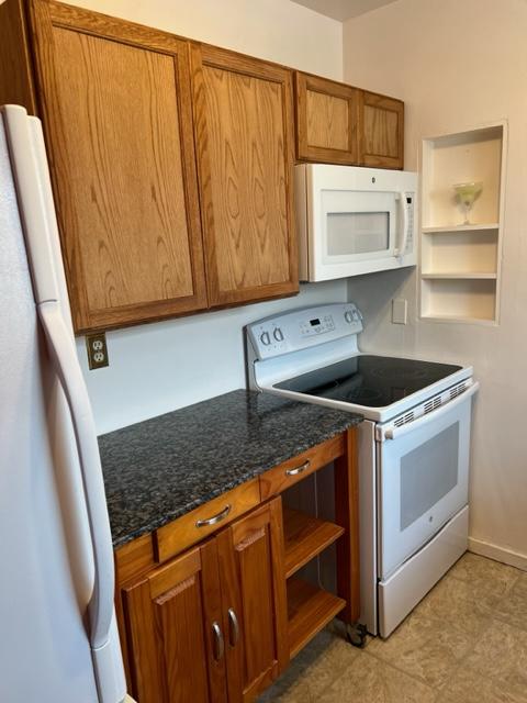 915 Hauser Blvd, Helena, MT 59601 - kitchen with white appliances, open shelves, brown cabinetry, and dark stone countertops