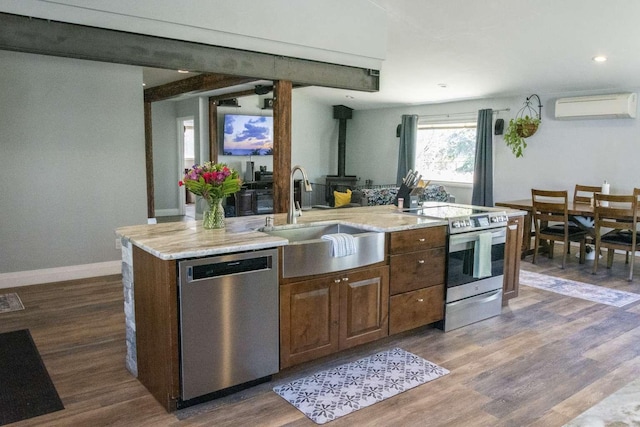 179 Fairmont Rd, Kalispell, MT 59901 - kitchen with stainless steel appliances, a sink, an AC wall unit, a wood stove, and wood finished floors