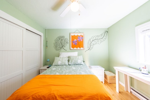 102 Scenery Rd, Libby, MT 59923 - bedroom featuring light wood-style flooring, a baseboard heating unit, a ceiling fan, and a closet