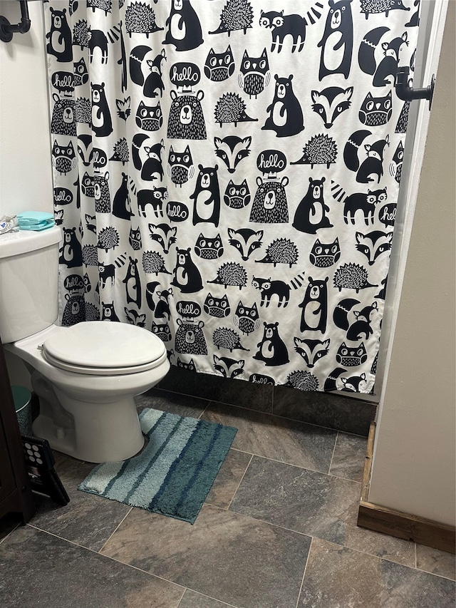 bathroom featuring stone tile flooring, toilet, and a shower with curtain