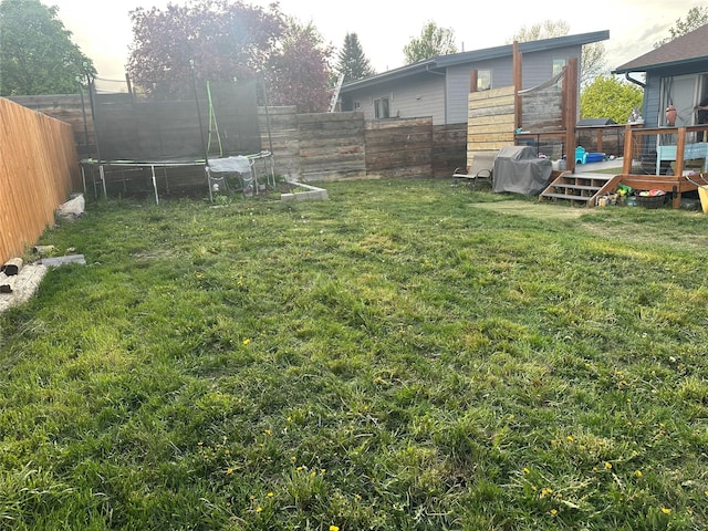 view of yard featuring a trampoline and a deck