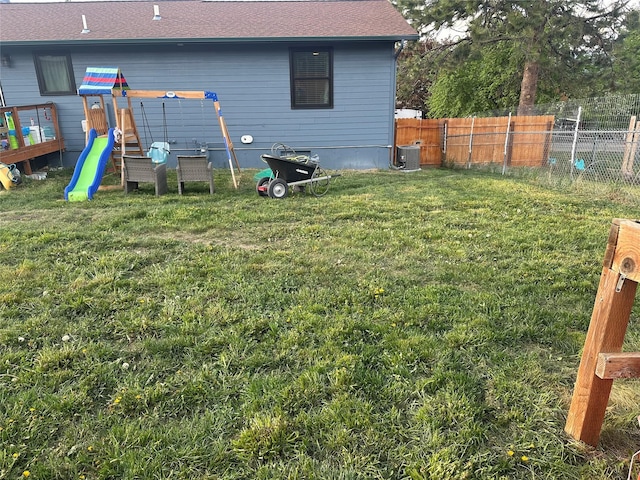 back of house with central air condition unit, a playground, and a shingled roof