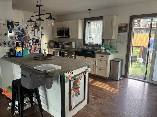 kitchen featuring stainless steel appliances, a sink, dark countertops, and plenty of natural light