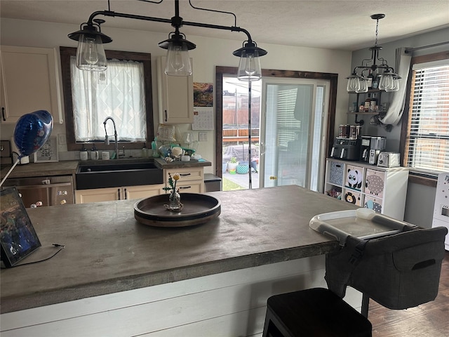 kitchen with a sink, dark countertops, white cabinets, and decorative light fixtures