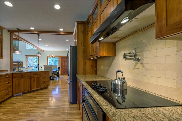10758 Sleeman Creek Rd, Lolo, MT 59847 - kitchen featuring brown cabinetry, under cabinet range hood, black appliances, a chandelier, and light wood finished floors