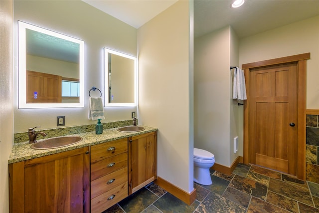 10758 Sleeman Creek Rd, Lolo, MT 59847 - bathroom featuring stone tile flooring, baseboards, toilet, and double vanity