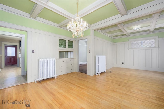 843 Lewisohn St, Butte, MT 59701 - empty room featuring radiator heating unit, coffered ceiling, light wood-style flooring, a chandelier, and a decorative wall