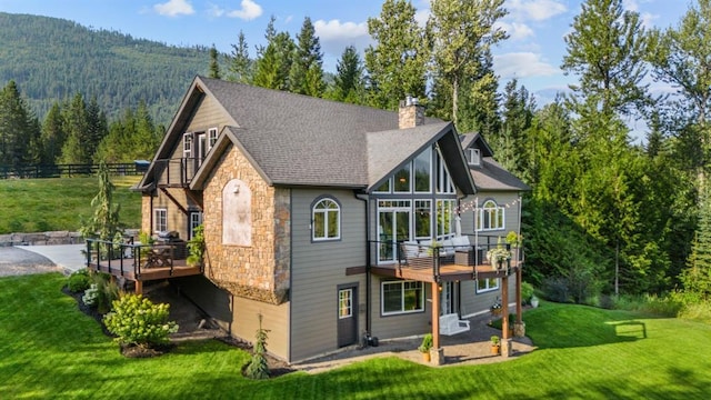 15 Sandi Ln, Heron, MT 59844 - back of house featuring stone siding, a balcony, a forest view, a chimney, and a deck