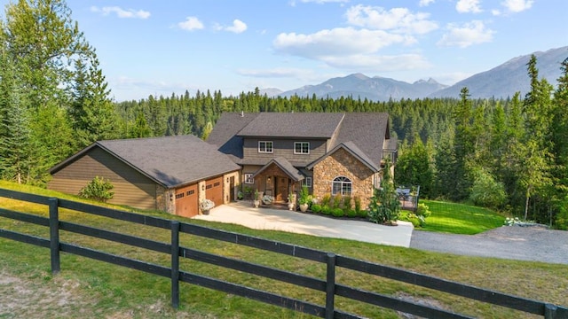 15 Sandi Ln, Heron, MT 59844 - view of front of house with stone siding, a garage, driveway, a mountain view, and a view of trees