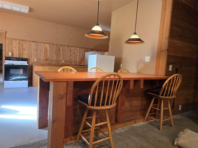 401 Western Larch Ln, Yaak, MT 59935 - kitchen with electric range oven, freestanding refrigerator, butcher block countertops, a kitchen bar, and wooden walls