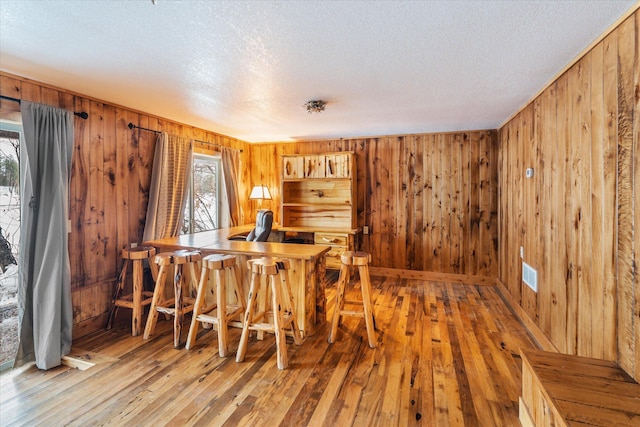 655 Leksand Trl, Whitefish, MT 59937 - dining room with wooden walls, a textured ceiling, light wood finished floors, and a bar