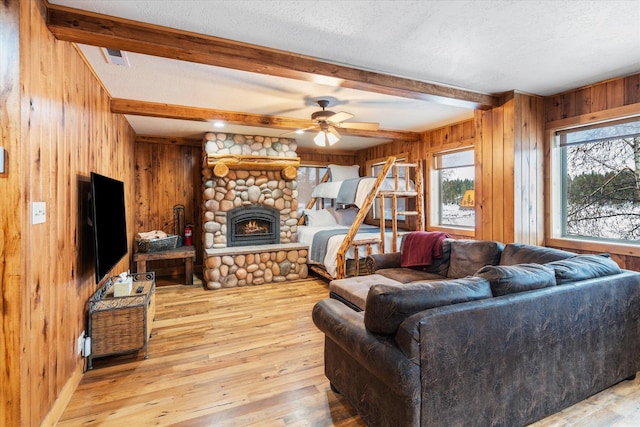 655 Leksand Trl, Whitefish, MT 59937 - living area featuring wood walls, a stone fireplace, ceiling fan, a textured ceiling, and beam ceiling