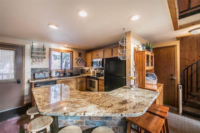97 Cedar Way Unit 97, Whitefish, MT 59937 - kitchen featuring black appliances, a sink, a breakfast bar area, light stone counters, and recessed lighting