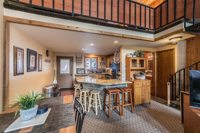 97 Cedar Way Unit 97, Whitefish, MT 59937 - kitchen with a peninsula, recessed lighting, freestanding refrigerator, a kitchen breakfast bar, and light stone countertops
