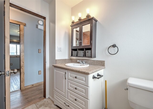 bathroom featuring toilet, vanity, and baseboards