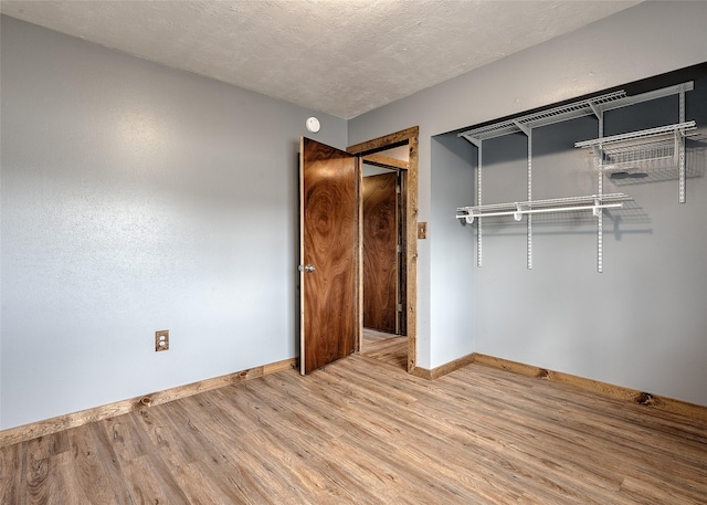 unfurnished bedroom with baseboards, wood finished floors, a closet, and a textured ceiling