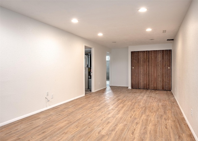 unfurnished room featuring light wood finished floors, recessed lighting, and baseboards