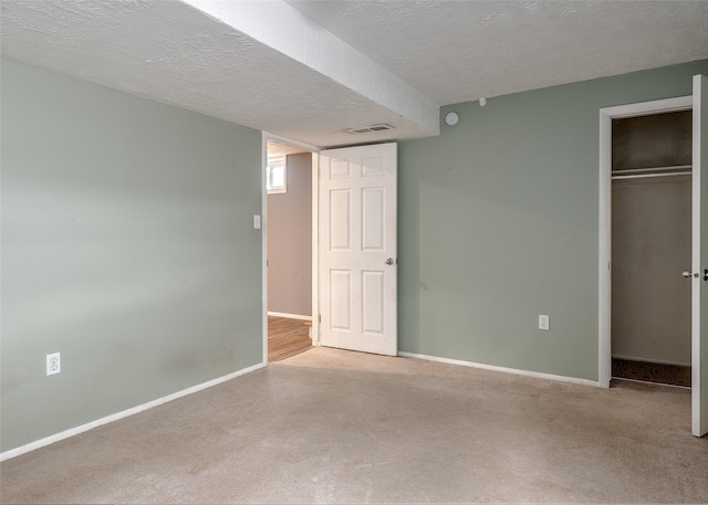 unfurnished bedroom featuring a textured ceiling, a closet, baseboards, and carpet