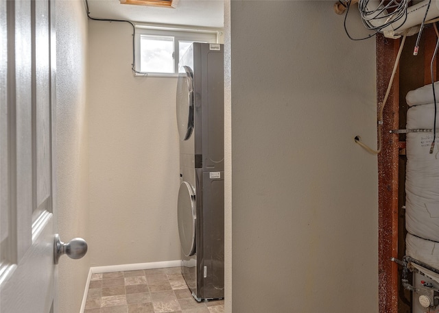laundry room featuring stacked washer and clothes dryer and baseboards