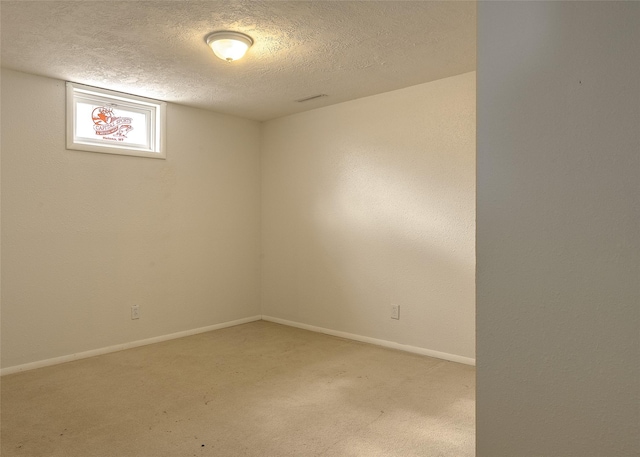 empty room featuring a textured ceiling, light colored carpet, and baseboards