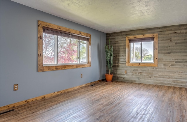 spare room featuring wood finished floors, wooden walls, and baseboards