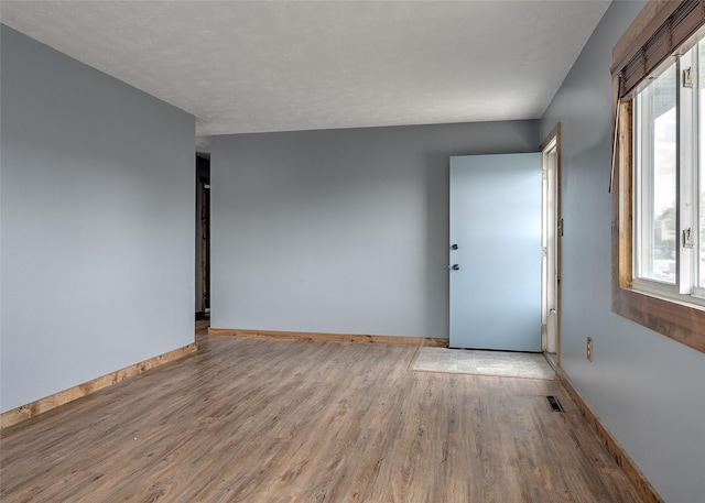 spare room with light wood-style floors, baseboards, and healthy amount of natural light