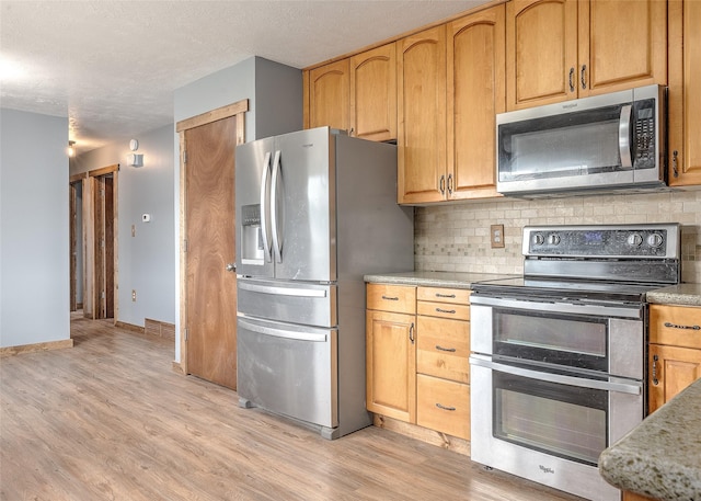 kitchen featuring stainless steel appliances, decorative backsplash, light wood-style floors, and a textured ceiling