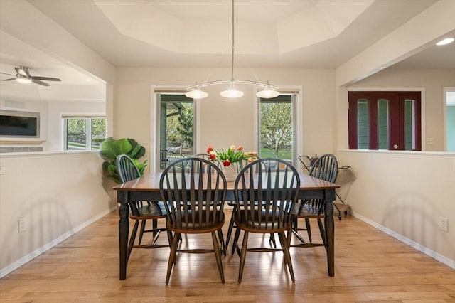 dining area with a raised ceiling, light wood-style flooring, baseboards, a ceiling fan, and recessed lighting
