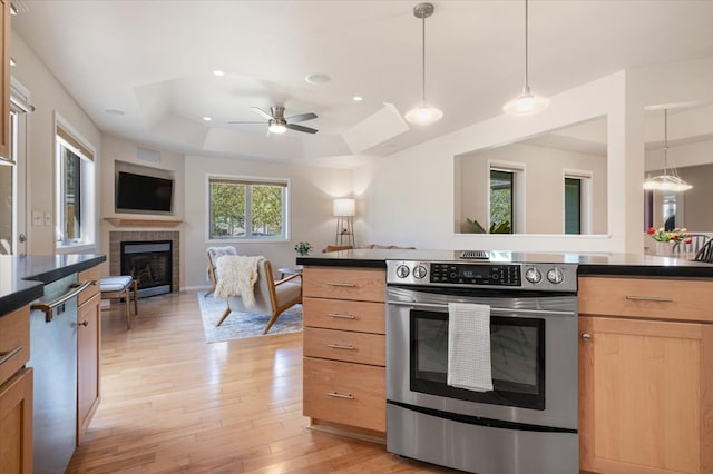 kitchen featuring appliances with stainless steel finishes, a raised ceiling, open floor plan, a fireplace, and dark countertops