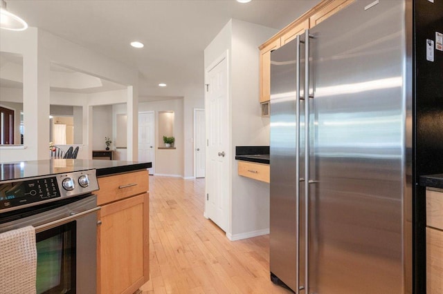kitchen featuring appliances with stainless steel finishes, light brown cabinets, dark countertops, light wood-type flooring, and recessed lighting