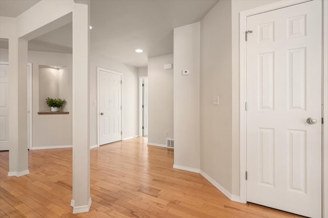 hallway featuring light wood-style floors, baseboards, and recessed lighting
