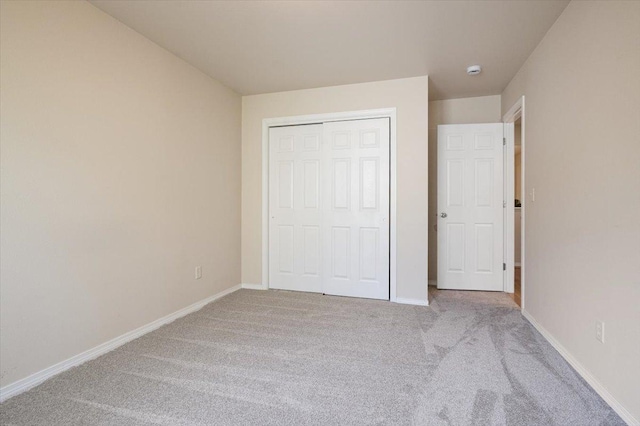 unfurnished bedroom featuring carpet, baseboards, and a closet