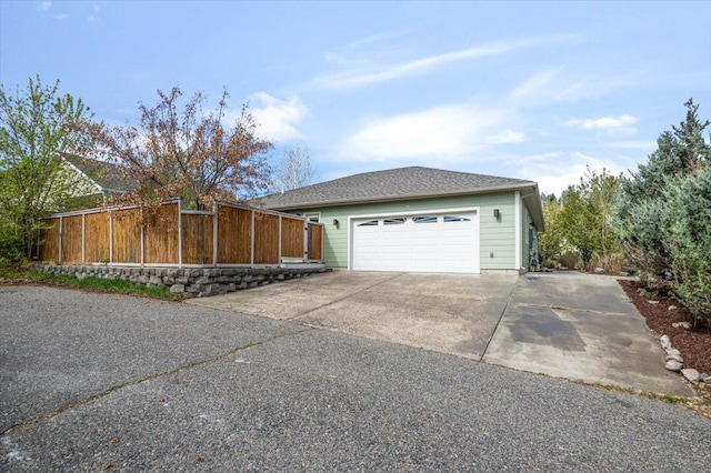 view of side of property with fence, driveway, and a garage