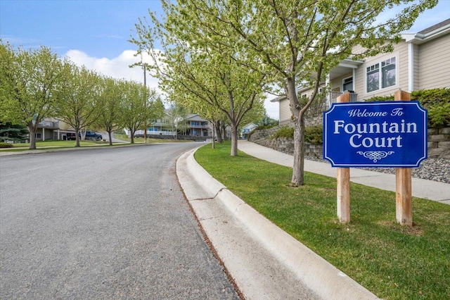 view of asphalt street featuring curbs, sidewalks, and a residential view