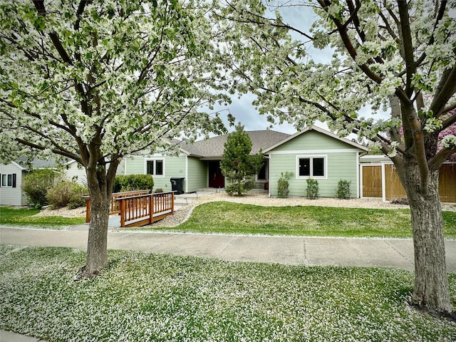 single story home featuring a shingled roof and a wooden deck