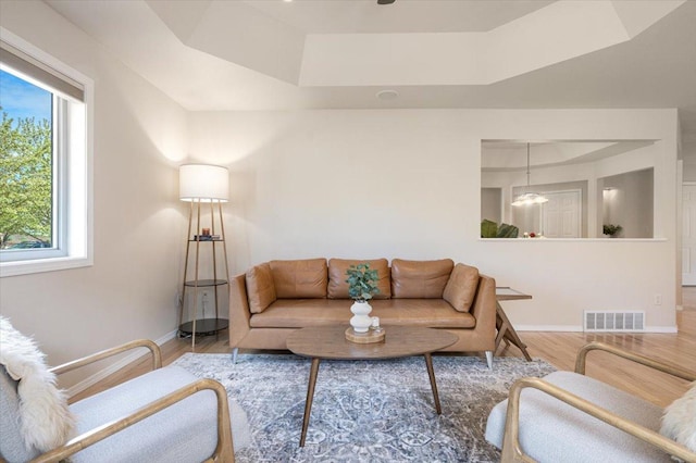 living area with a raised ceiling, wood finished floors, and baseboards