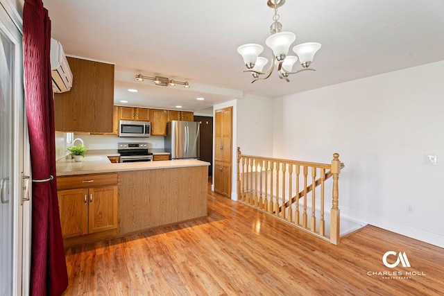 kitchen featuring appliances with stainless steel finishes, a peninsula, light wood-style flooring, light countertops, and brown cabinetry