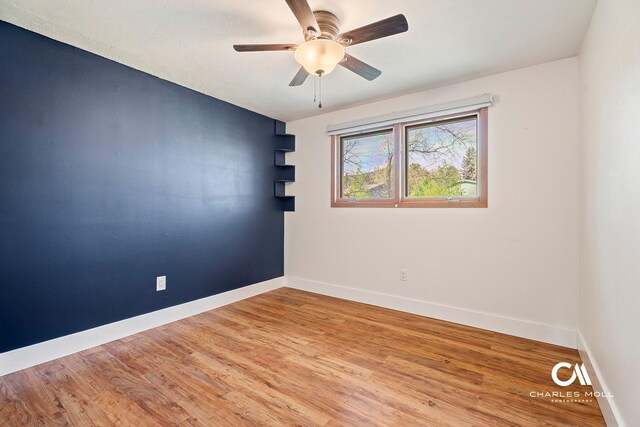 unfurnished room with baseboards, a ceiling fan, and wood finished floors