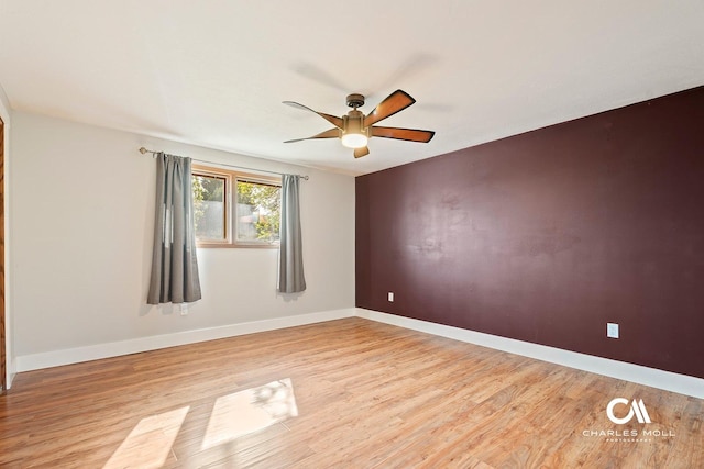 spare room featuring light wood-type flooring, a ceiling fan, and baseboards