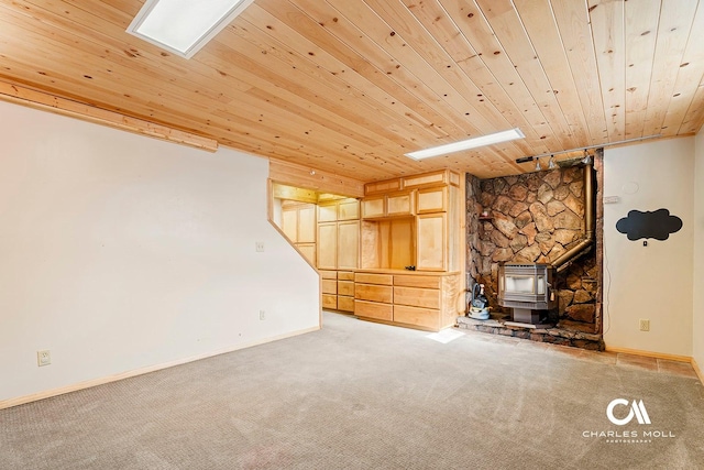 below grade area featuring a wood stove, wooden ceiling, heating unit, carpet flooring, and baseboards