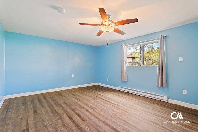 spare room with baseboard heating, ceiling fan, wood finished floors, baseboards, and a smoke detector