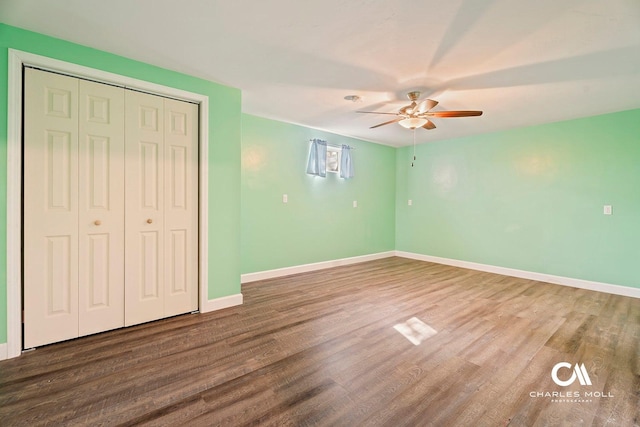 unfurnished bedroom featuring wood finished floors, baseboards, a closet, and a ceiling fan