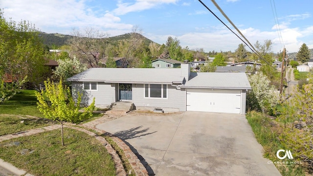 view of front of property with a garage, driveway, a chimney, and a mountain view