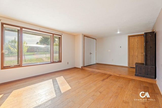 unfurnished living room with light wood-style flooring and baseboards