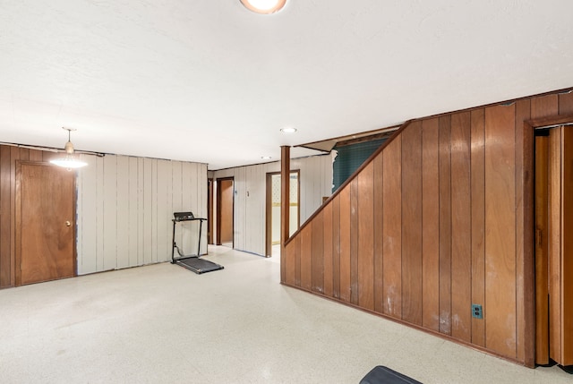 finished below grade area with wooden walls, stairway, and light flooring