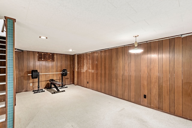 exercise room with wood walls and carpet flooring