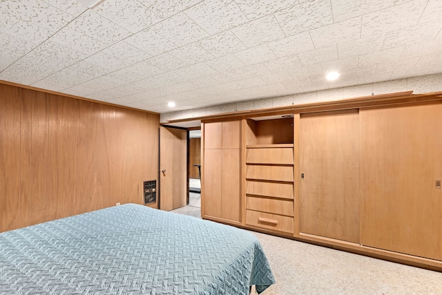 carpeted bedroom featuring heating unit and wooden walls